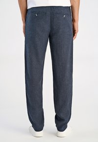 Spodnie w marynarskie paski wykonane z teksturowanej tkaniny, z dwiema tylnymi kieszeniami ozdobionymi guzikami i luźnym krojem.