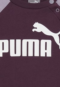 Mörklila sweatshirt med grå raglanärmar. Framsidan visar en stor vit "PUMA"-logotyp och det karaktäristiska pumasilhuett.