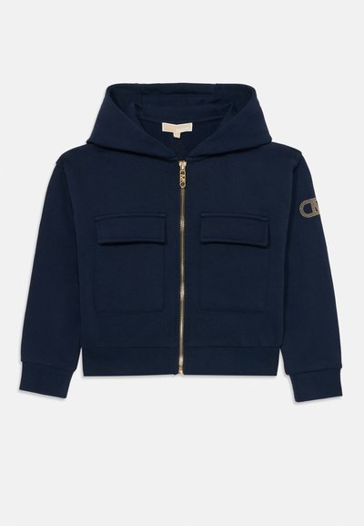 Sweat à capuche zippé bleu marine avec poches avant à rabat, manches longues et un logo discret sur la manche gauche.
