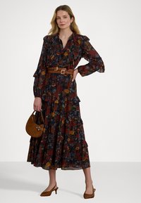 Garšīgs ziedu kleita tumšās krāsās, kas rotāta ar volāniem pie apkakles un piedurknēm, jostu ap vidu un kārtotu svārku. Aksesuāri ietver mazu brūnu somu.