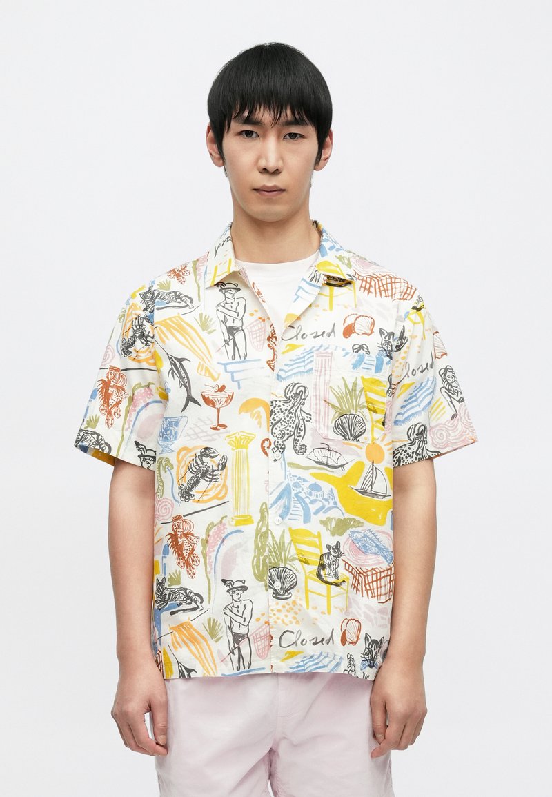 Κοντομάνικο πουκάμισο με γιακά, κατασκευασμένο από ελαφρύ ύφασμα με πολύχρωμο, αφηρημένο σχέδιο που περιλαμβάνει διάφορες εικονογραφήσεις και σχήματα.