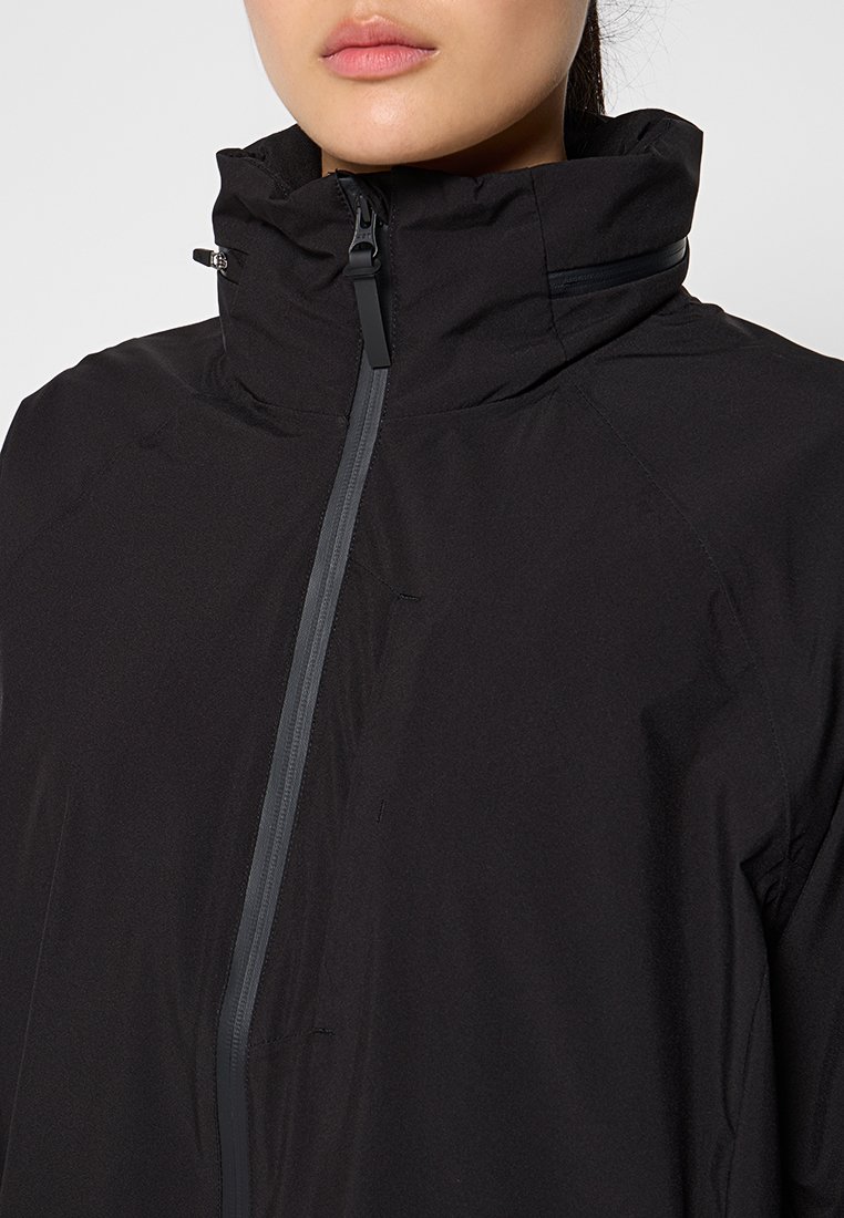 Schwarze Jacke mit hohem Kragen, durchgehendem Reißverschluss und einer glatten, matten Textur. Sie hat dezente Nahtdetails für einen modernen Look.