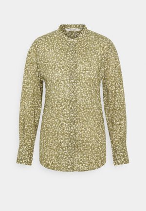 Camicia verde floreale a maniche lunghe con colletto rialzato, in tessuto leggero, e un motivo di piccoli fiori bianchi e gialli su tutta la superficie.