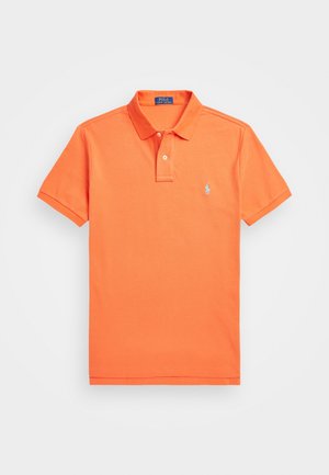 Polo majica s kratkimi rokavi v svetlo oranžni barvi iz bombaža, s ovratnikom, dvema gumboma na sprednji strani in vezenim modrim logotipom na prsih.