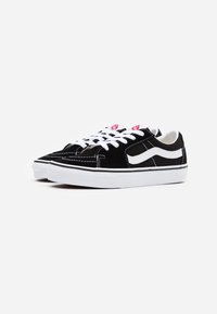 Schwarze Wildleder-Low-Top-Sneaker mit weißen Gummisohlen, weißen Nähten und klassischem Seitenstreifen-Design. Mit weißen Schnürsenkeln und roten Logo-Akzenten.