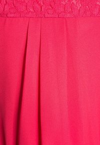 La tela rosa presenta pliegues texturizados y un detalle de encaje en la parte superior, mostrando un acabado suave y un color vibrante.