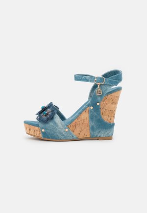 Sandale à talon compensé en denim bleu avec un coussinet en liège, détail floral à l'avant et bride à la cheville. Comprend des accents en métal doré et une surface texturée.