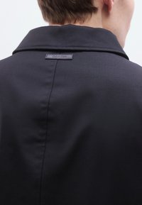 Μαύρο σακάκι ραμμένο στα μέτρα με λεία υφή, που διαθέτει μεγάλο γιακά και ετικέτα με το λογότυπο Calvin Klein στην πλάτη κοντά στη γραμμή του λαιμού.