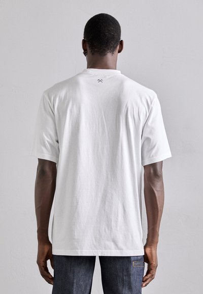 Weißes Baumwoll-T-Shirt mit kurzen Ärmeln, rundem Ausschnitt und einem kleinen Kreuzmuster auf dem Rücken. Der Stoff wirkt glatt und lässig.