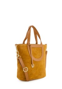 Tan suède tote bag met bruine leren accenten, voorzien van dubbele handvatten en een afneembare schouderriem, gladde textuur en minimale hardware.
