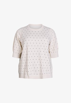 Kremowy sweter wykonany z miękkiego materiału, ozdobiony czarnymi kropkami, z okrągłym dekoltem i krótkimi, bufkowatymi rękawami.