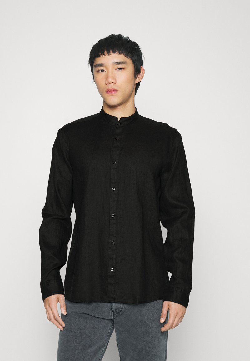 Zwarte, langwaardige blouse met een knoopsluiting aan de voorkant, een zachte textuur en een mandarinnekraag. Kenmerkt zichtbare knopen en een ontspannen pasvorm.