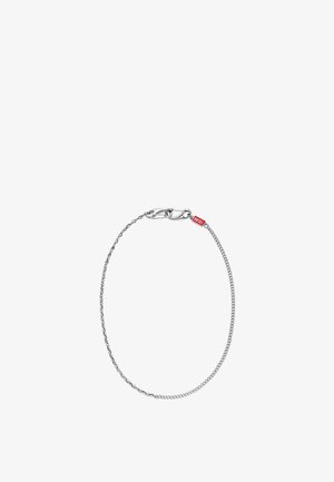 Bracciale a catena sottile in argento con chiusura a moschettone e piccola targhetta rettangolare rossa con la scritta "DIESEL" su sfondo bianco.