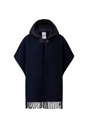 Navy wool poncho with a black quilted hood, featuring a button closure, vertical stitching, and fringe detailing along the bottom edge.