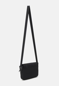 Borsa a tracolla nera con esterno in tessuto morbido, forma rettangolare, tracolla regolabile e chiusura a pattina. Presenta una tasca con zip sul retro.