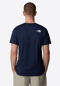 Marineblå bomulds T-shirt med korte ærmer. Har et hvidt logo på øverste ryg. Glat tekstur, klassisk rund hals design.