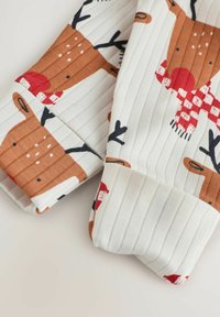 Ruskea ja valkoinen kuviollinen neulekangas, jossa on hirvi- ja jouluteemaisia motiiveja, ribbitekstuuri ja pehmeä pinta. Reunat on siististi kantattu.