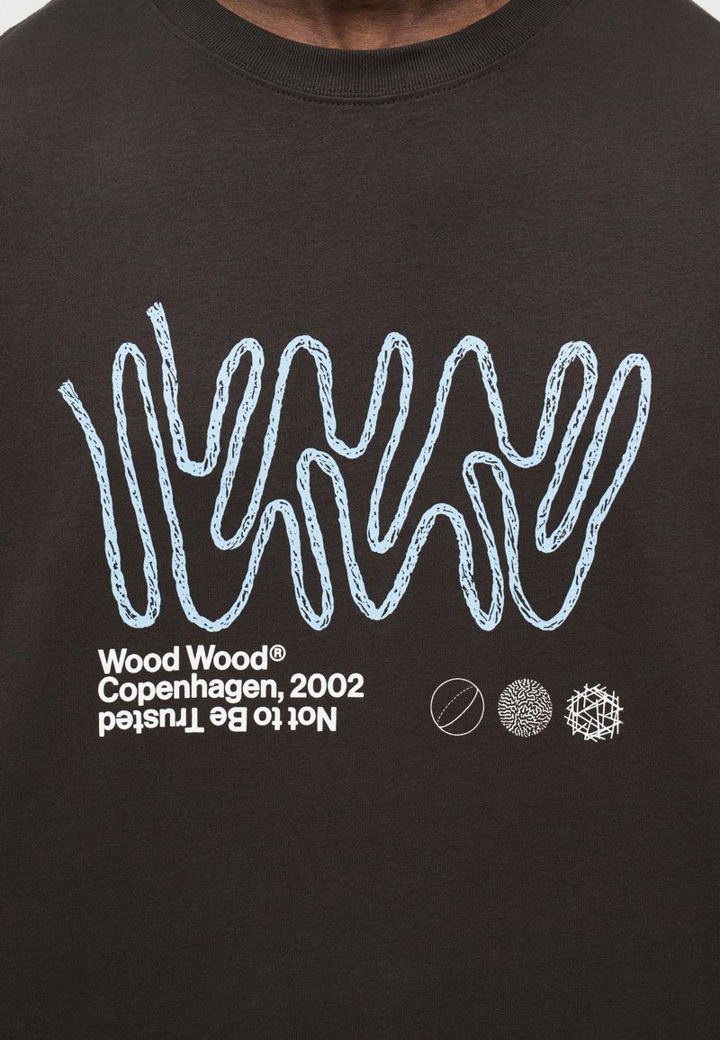Dark brown fabric with light blue wavy line pattern, white text "Wood Wood Copenhagen, 2002 Not to Be Trusted" and three small abstract circle icons.