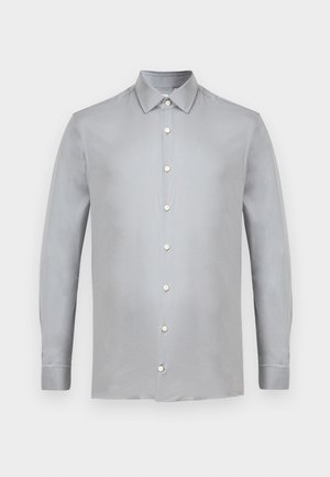 Chemise à manches longues gris clair, en tissu doux. Elle possède un col pointu et six boutons assortis sur le devant.