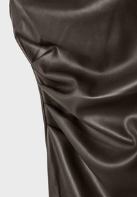 Tamno smeđa umjetna koža s glatkom teksturom, s blagim naborima i naborima koji stvaraju dinamičan vizualni efekt.