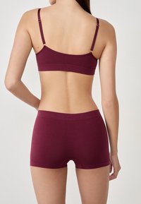 Ensemble bralette et short en marron, doté de bretelles ajustables, d'une texture douce, de bords sans couture et d'un design ajusté avec une esthétique minimaliste.