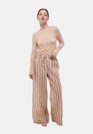 Haut beige à manches longues associé à un pantalon large avec des rayures verticales rouges et beiges, taille à cordon de serrage et texture de tissu douce.