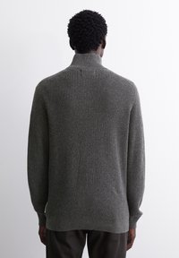 Grauer gerippter Strickpullover mit Stehkragen, langen Ärmeln und strukturiertem Finish. Entworfen mit einem lockeren Schnitt und leichten überschnittenen Schultern.