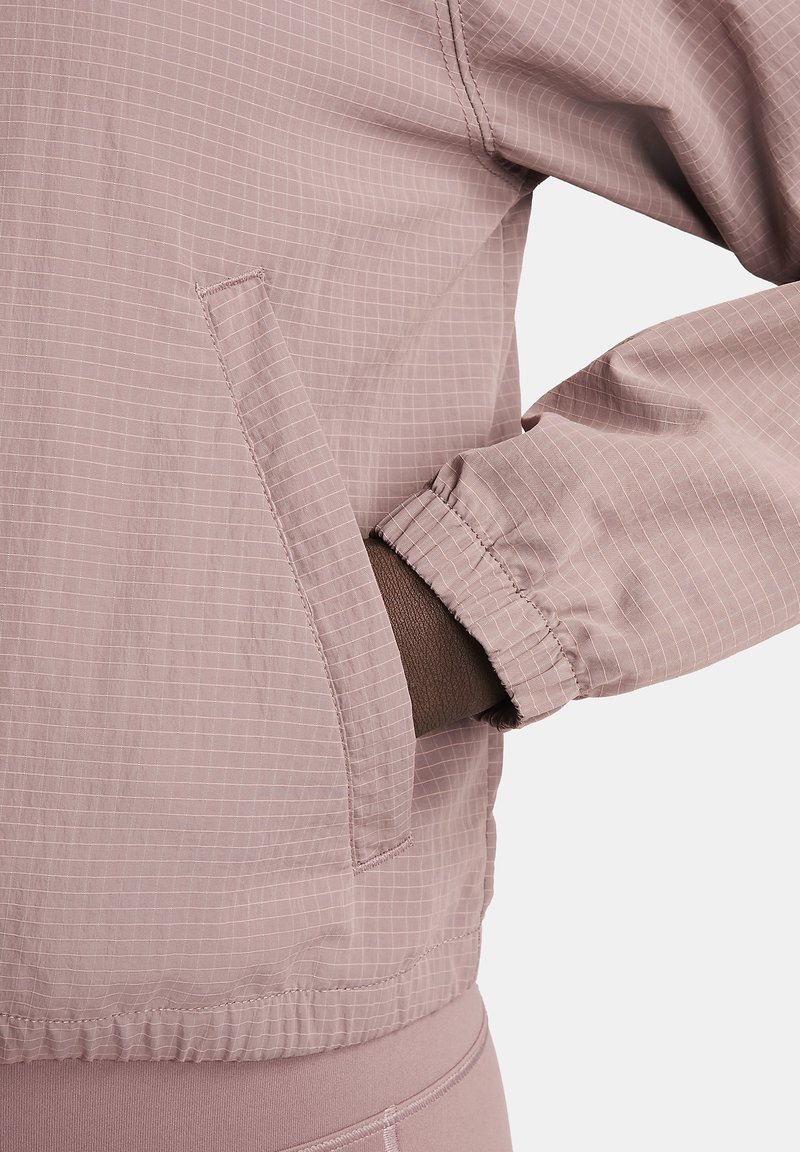 Lichtroze windbreakerjack met een ruitpatroon, elastische manchetten en zijzakken. Gemaakt van zacht, lichtgewicht materiaal.