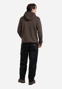 Brown hooded sweatshirt with a relaxed fit, paired with black pants. The texture appears smooth with a logo patch on the pants.