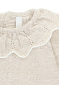 Suéter de punto color crema que presenta un cuello con forma de concha con ribete blanco y un patrón texturizado. Material suave y liviano con escote redondo.