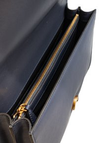 Borsa in pelle blu navy con una tasca con zip dorata e un interno morbido. Presenta una superficie liscia e bordi superiori arrotondati.