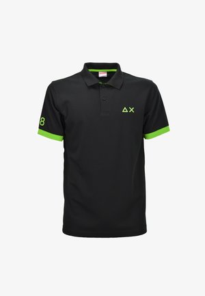 Camiseta polo negra con forro de cuello y puños de manga en verde neón, con logo geométrico verde en el pecho y número 8 en la manga derecha.