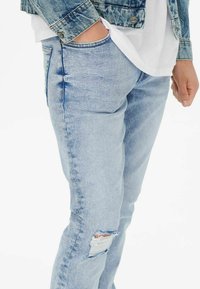 Light blue denim jeans with a slim fit, featuring a distressed knee detail and subtle fading. Pairing with a denim jacket.