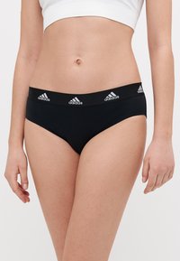 Černé bavlněné bikiny se širokým elastickým pasem s opakujícími se bílými logy Adidas. Hladká textura, střední výška.