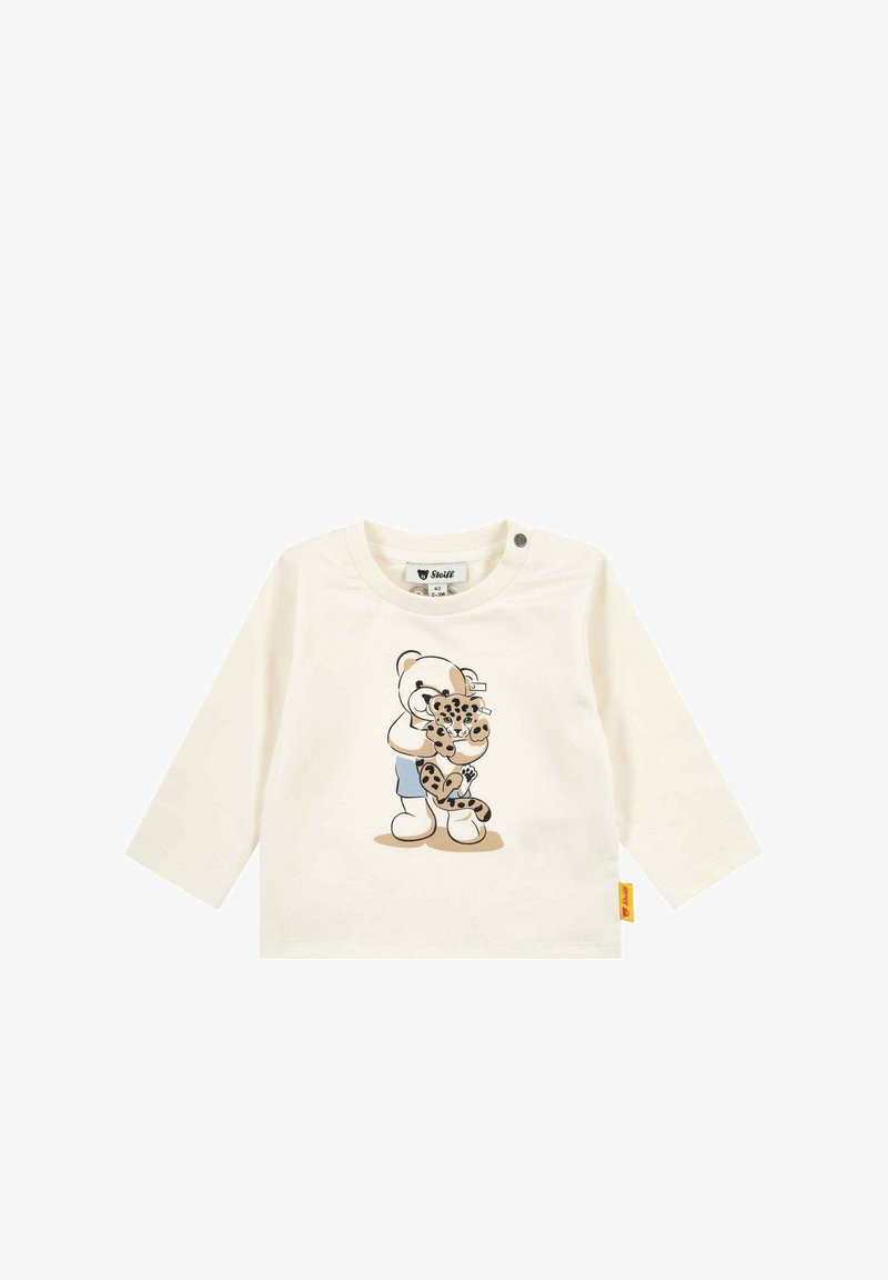 Camiseta de bebé de manga larga color crema con estampado de un oso de peluche abrazando a un cachorro de leopardo, con botones a presión en el hombro y una etiqueta de marca amarilla.