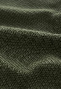 Textured fabric in olive green, featuring a tight, woven pattern that creates a subtle depth. Soft texture with a smooth finish.