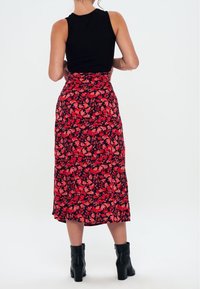 Sort ribbet tanktop kombineret med en rød blomster midi-skirt med en mørk baggrund, flared kant og sorte ankelstøvler.