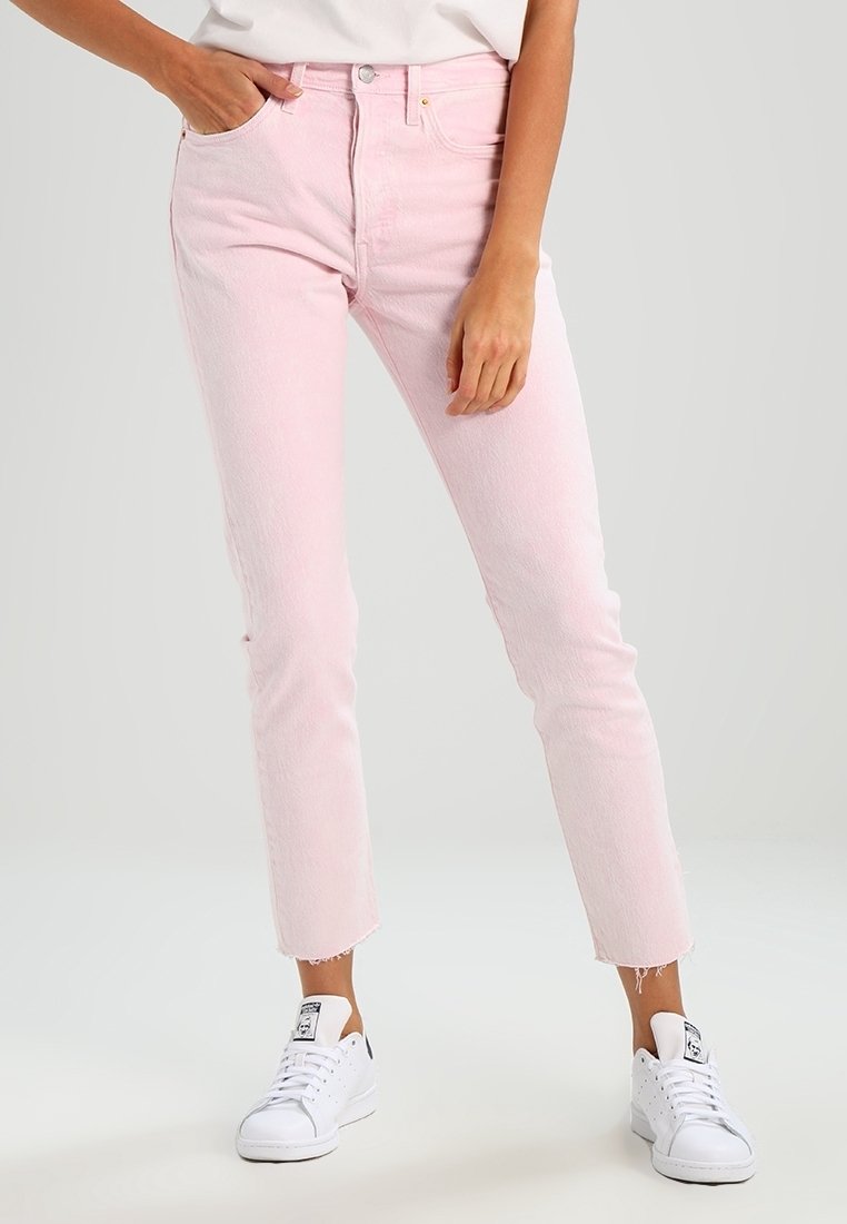 Rosa jeans med slim fit och rå kant, tillverkade av denim. Kombinerat med vita sneakers, vilket visar en avslappnad stil.