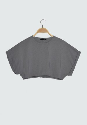 Grijs kort mouw cropped top met opgerolde manchetten aan houten hanger tegen een effen lichte achtergrond.