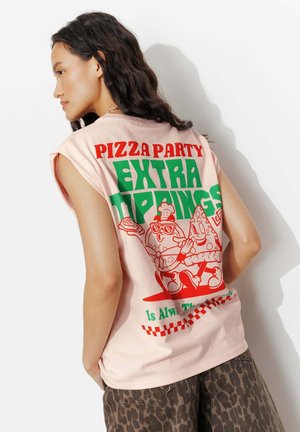 Jeune femme aux longs cheveux bruns portant un haut rose clair sans manches avec des textes et des motifs colorés sur le thème de la pizza dans le dos.