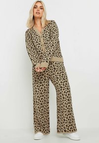 Beige leopardmönstrad lounge-set som består av en långärmad cardigan med V-ringning och vida byxor; tillverkad av mjukt stickat tyg.