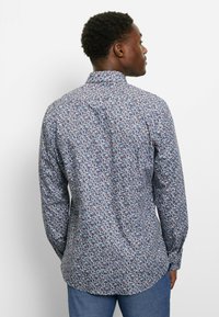 Langärmeliges Hemd in Dunkelblau mit einem Floralmuster in Pink, Weiß und Hellblau. Verfügt über einen klassischen Kragen und geknöpfte Manschetten.