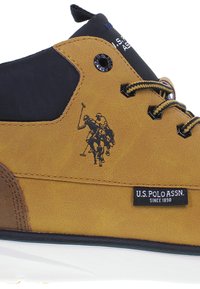 Sneakers sintetice bej cu accente din țesătură neagră, având un logo cu doi jucători de polo, șireturi negre și o talpă din cauciuc alb.