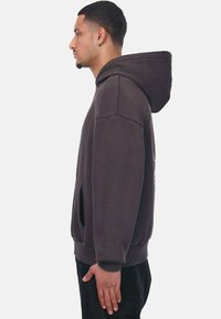 Dunkelgrauer Hoodie mit K�ängurutasche, ausgestattet mit einer Kapuze, überschnittenen Schultern und gerippten Bündchen. Glatter Stoff mit dezenten Nähdetails.