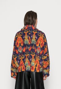 Fleecejack met een meerkleurig, abstract patroon met oranje, paars, groen en geel. Relaxte pasvorm met een hoge kraag.