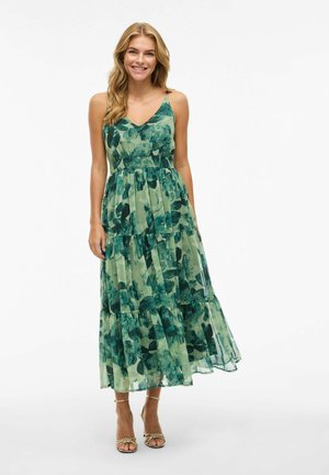Žalia gėlių motyvo midi suknelė su sluoksniuota dizaino, V formos iškirpte ir reguliuojamomis kaspino petnešomis. Pagaminta iš lengvos, permatomos medžiagos.