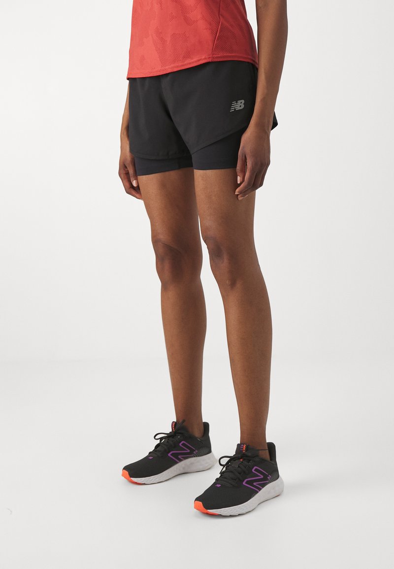 Black athletic shorts with a layered design, featuring a textured red tank top. Pair of black running shoes with purple and orange accents.
