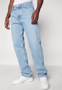 Lyseblå denimjeans med lige ben, der har en knap- og lynlåslukning, for- og baglommer samt synlige søm detaljer.