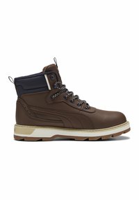 Bota alta de cuero marrón con cuello acolchado en color azul marino, cordones con patrón, entresuela beige y suela robusta marrón, mostrada en perfil lateral.