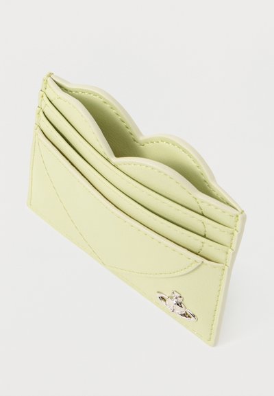 Φωτεινό πράσινο δερμάτινο θήκη καρτών με κυματιστές άκρες, πολλαπλές θήκες για κάρτες και μικρό ασημένιο έμβλημα σε σχήμα σφαίρας και δαχτυλιδιού.